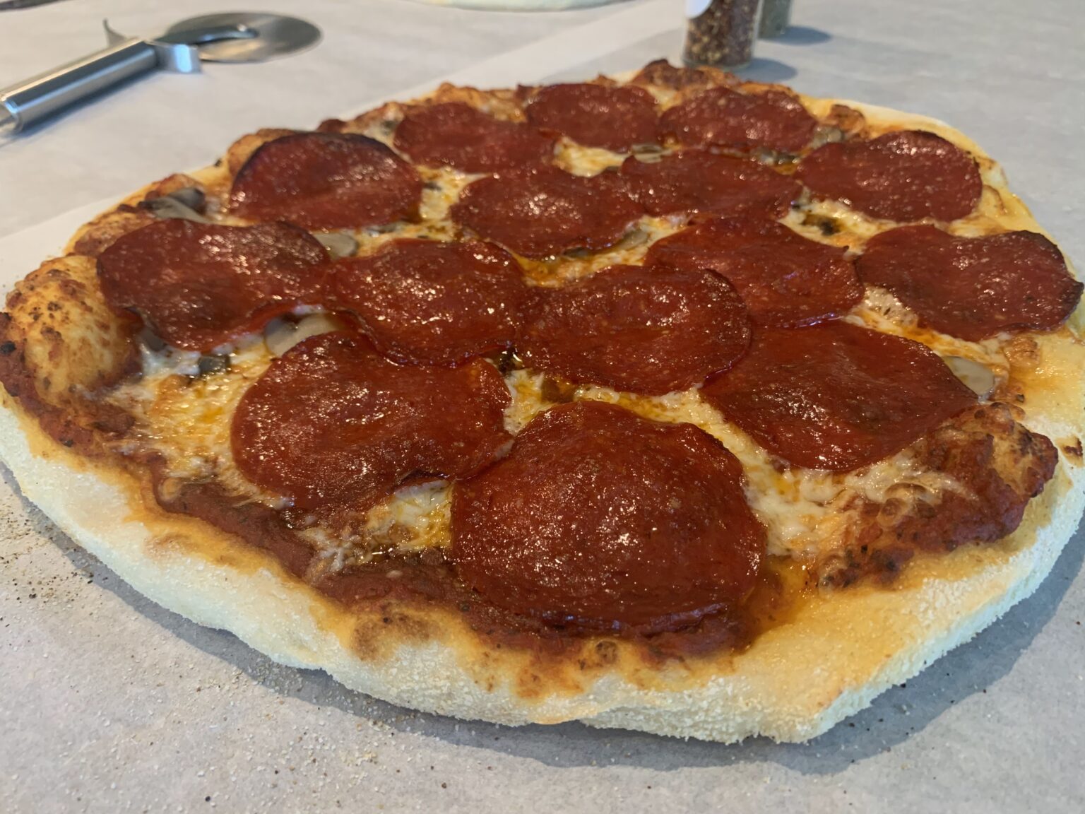 Picture of a cooked pizza that has red sauce, melted shredded cheese and pepperoni for toppings.