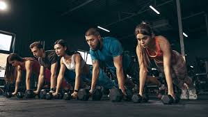 Group fitness class performing plank rows with dumbbells using proper RPE workout intensity